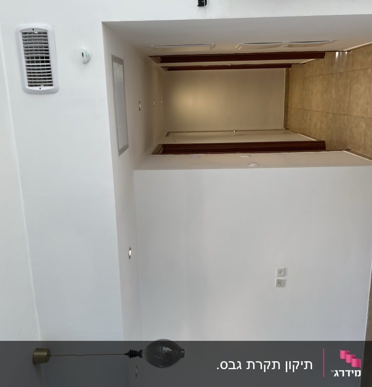 קיר גבס עם שקעי חשמל ומנורה תלויה